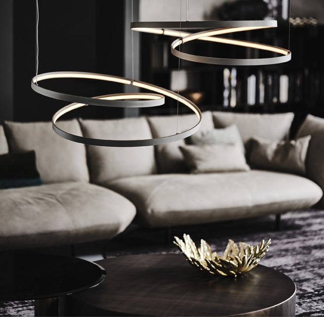 Modern chandelier lights contemporary living room with modern leather sofa, coffee table, and decor